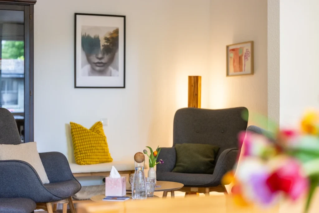 Raum für Psychotherapie mit bequemen blauen Sessel und Blumen.